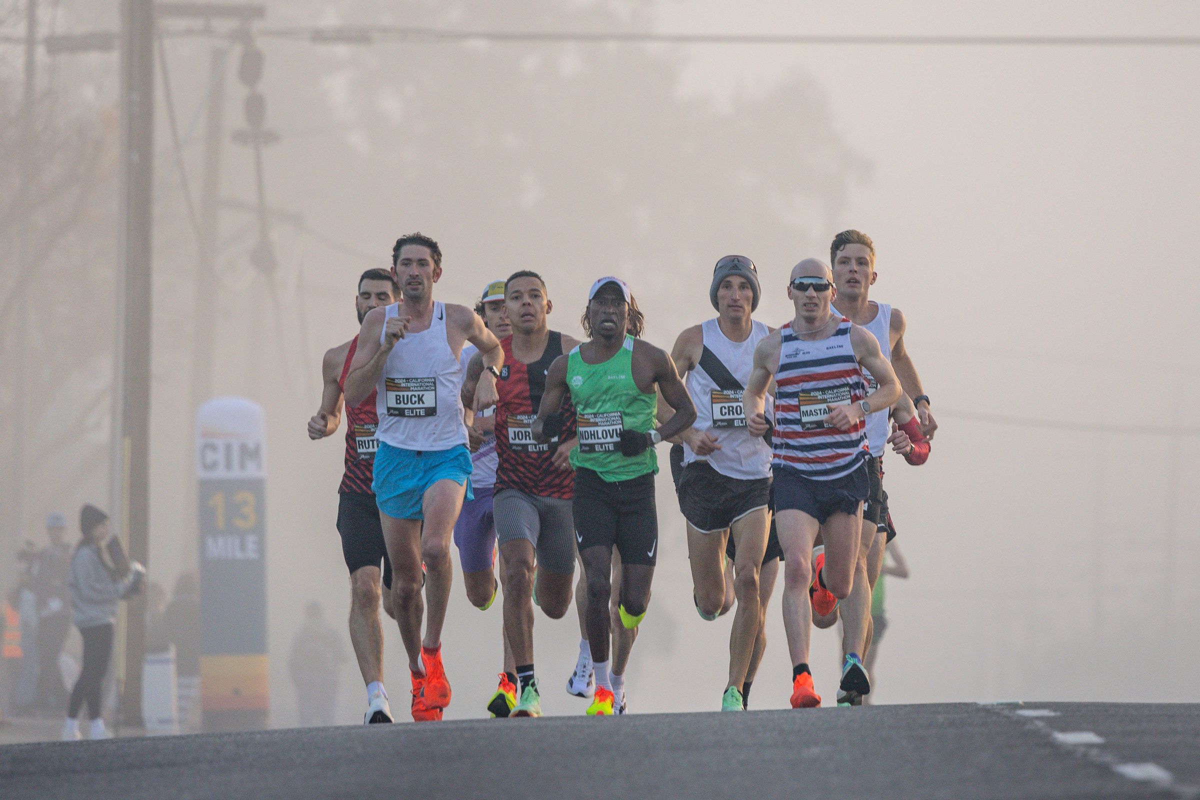 A pack of marathoners emerging from morning fog
